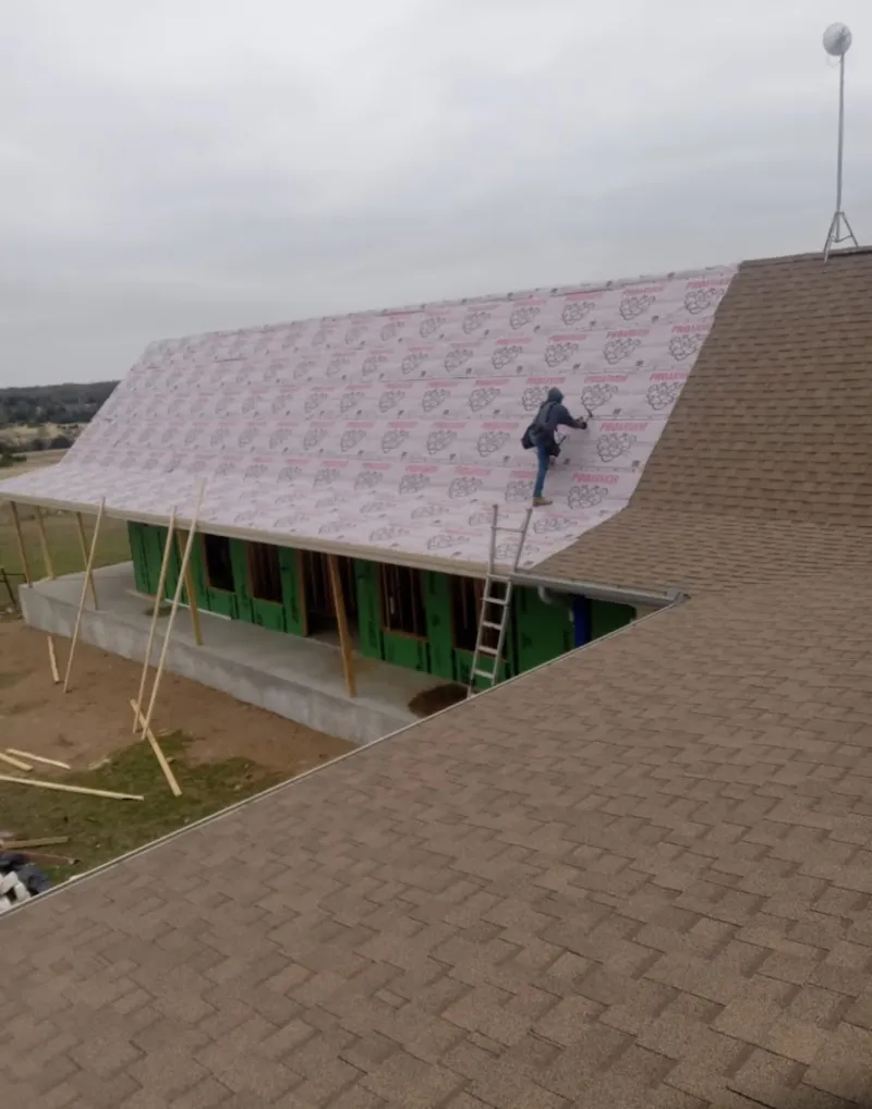 Worker preparing underlayment for a metal roof installation in Robinson